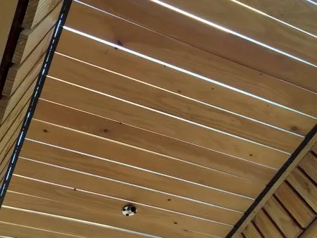 Plafond en bois avec des lattes espacées laissant passer la lumière naturelle, créant une ambiance chaleureuse et moderne.